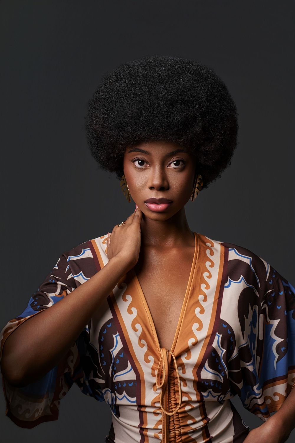 A series of fashion portraits showing a model wearing a patterned dress with brown and blue details against a dark background.
