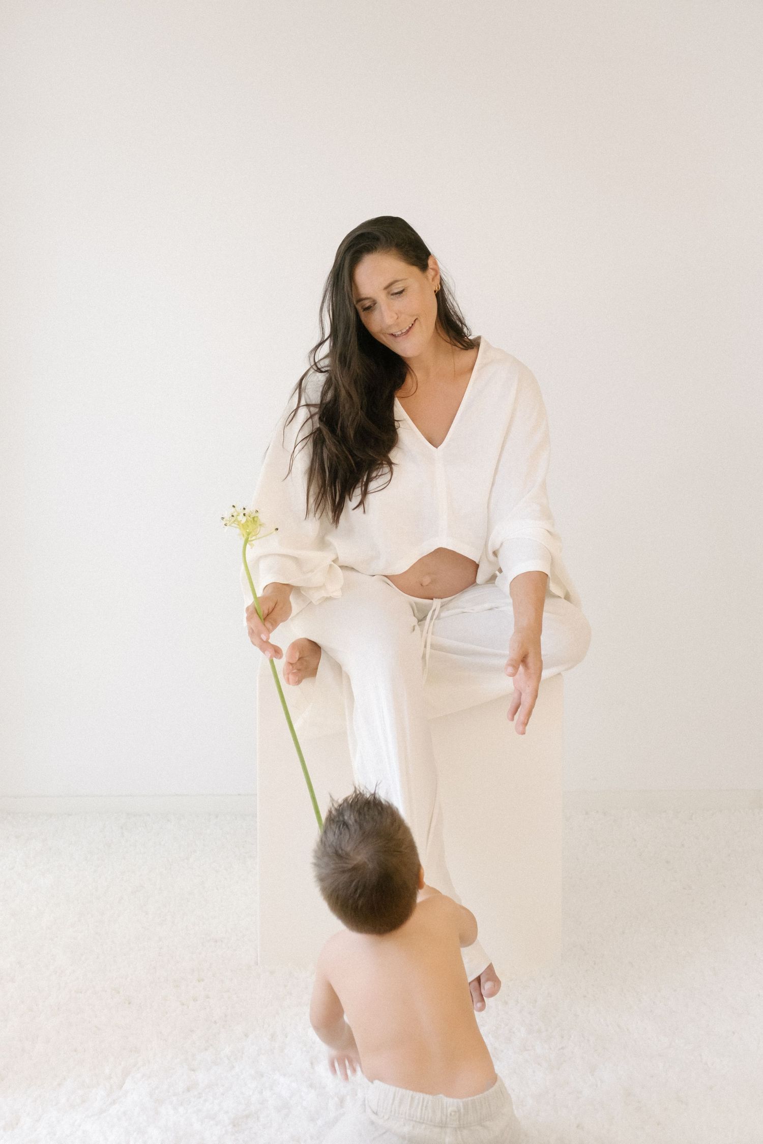 Intimate maternity photo session showing tender moments in white against neutral background.