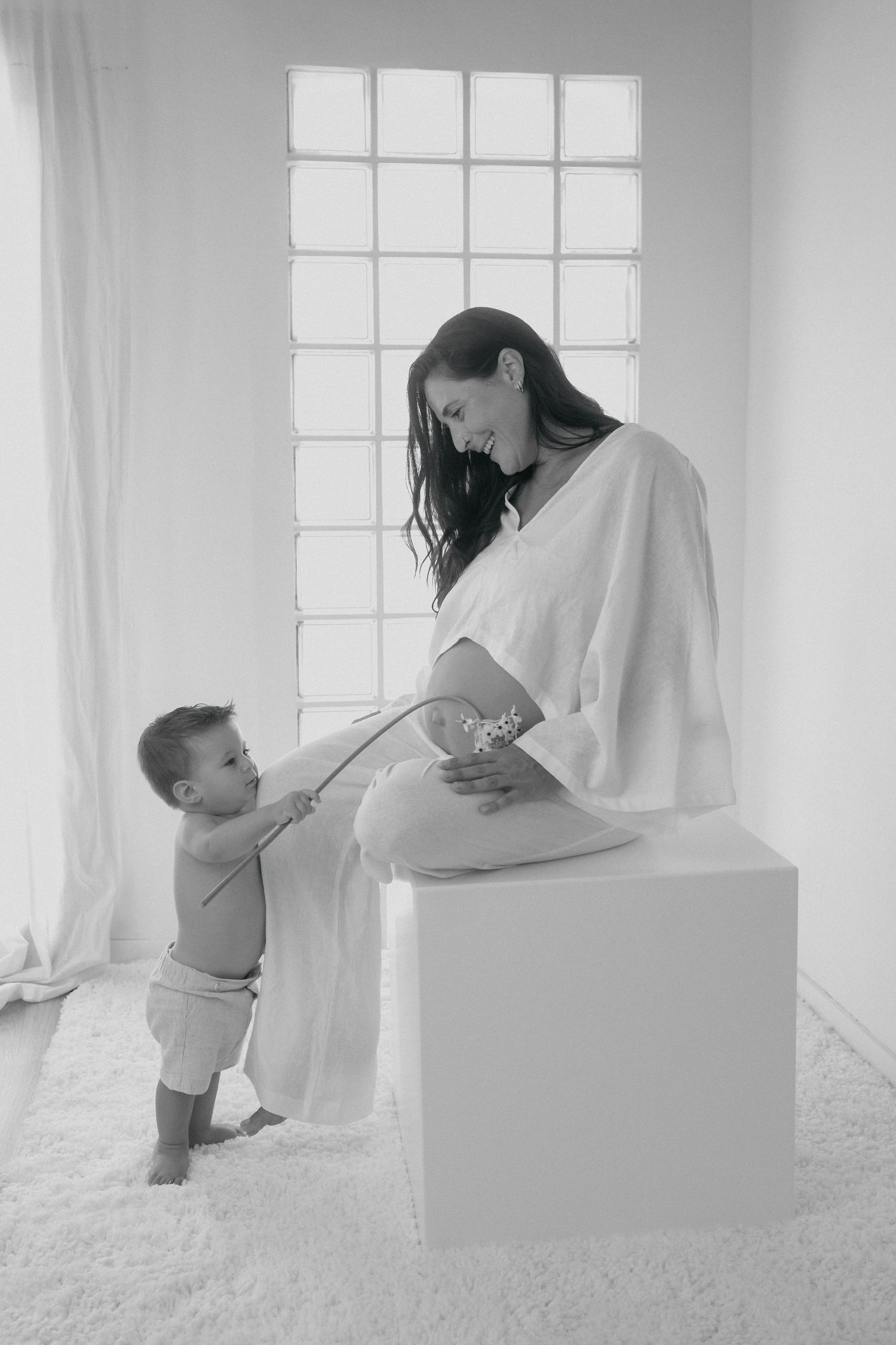 A tender maternity moment captured in black and white as a toddler reaches toward an expectant mother.