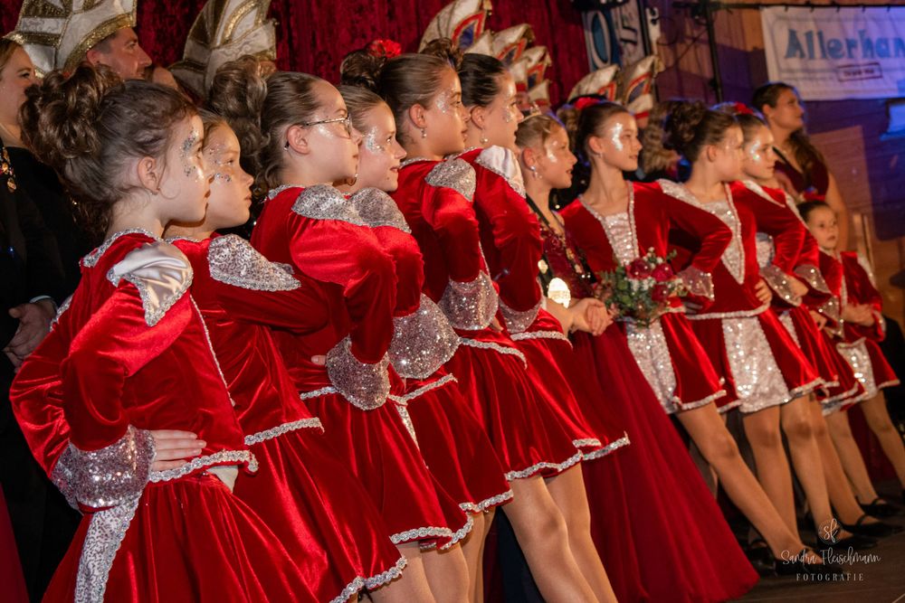 Choir performers in bright red robes stand in formation during a holiday concert performance.