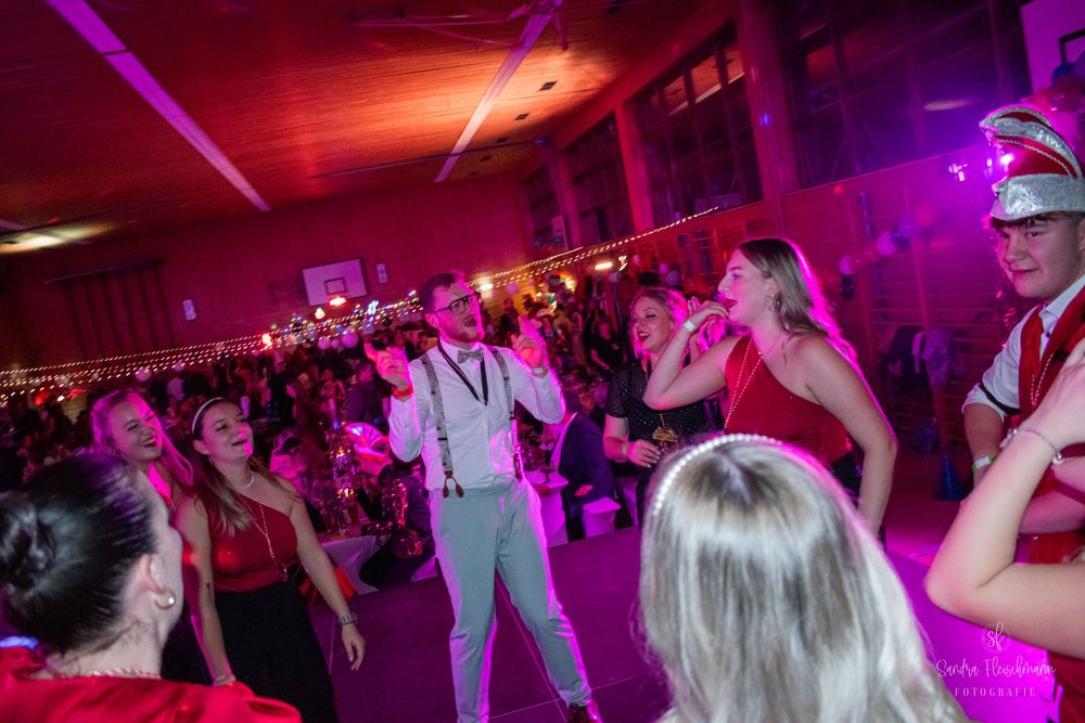 People dancing in a nightclub illuminated by vibrant purple lighting during a party event.