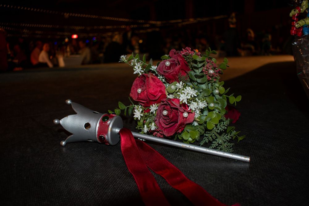 A bouquet of red roses with greenery lies next to a silver microphone on a dark surface.