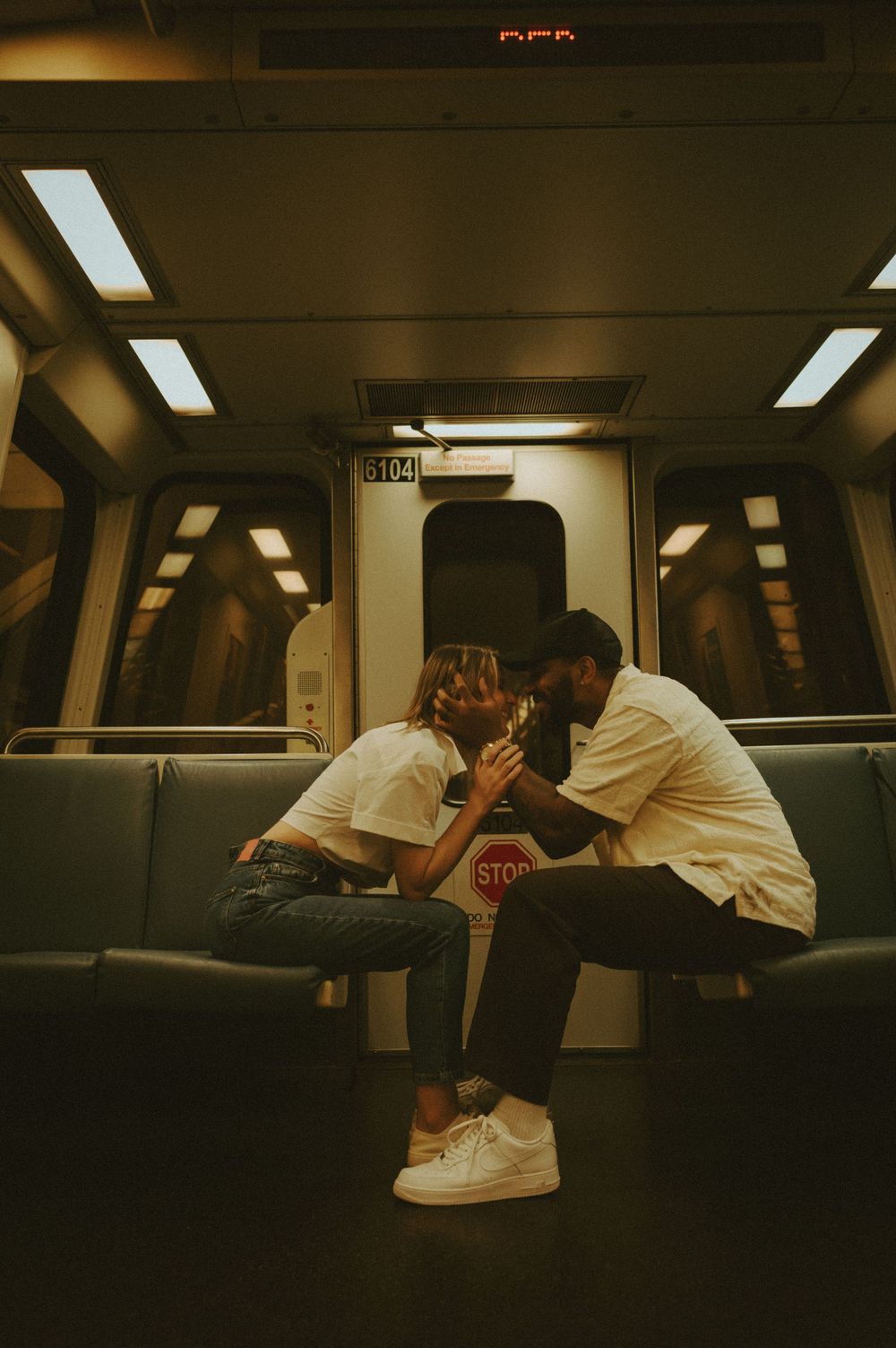 Two people relaxing on seats in a dimly lit subway car.