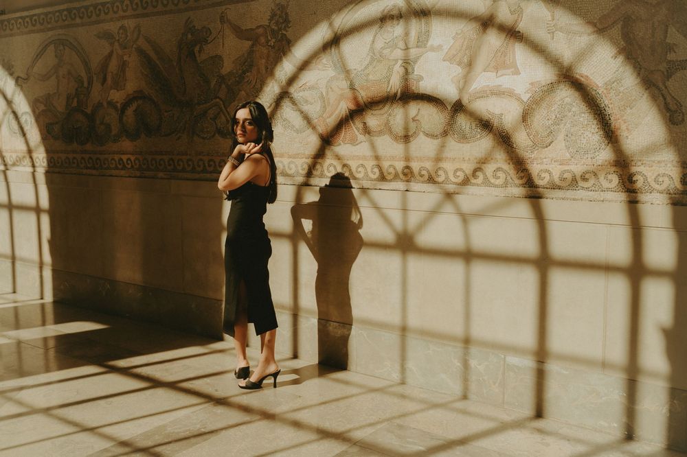 Sunlit archways create geometric patterns on a stone corridor floor.