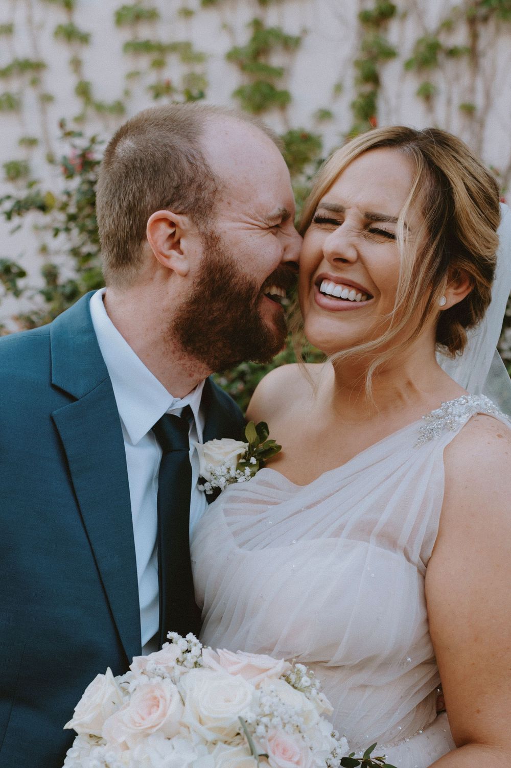 A candid wedding moment capturing laughter and joy between a couple in formal attire.
