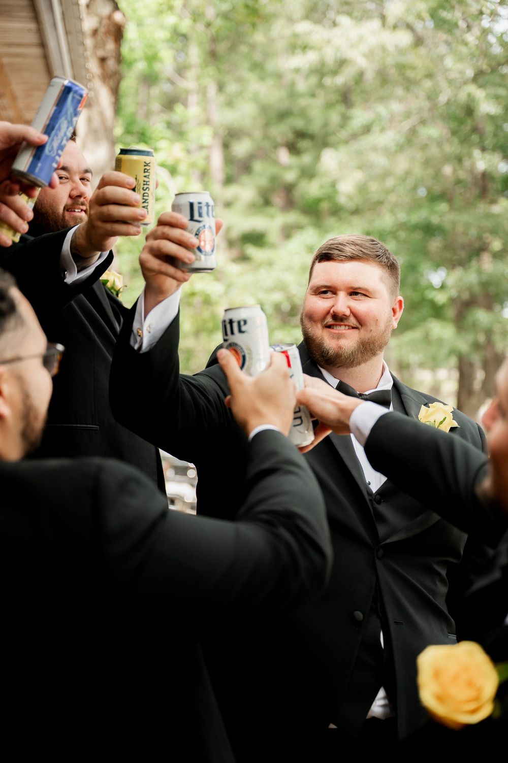 Wedding party members toast with drinks during outdoor celebration.
