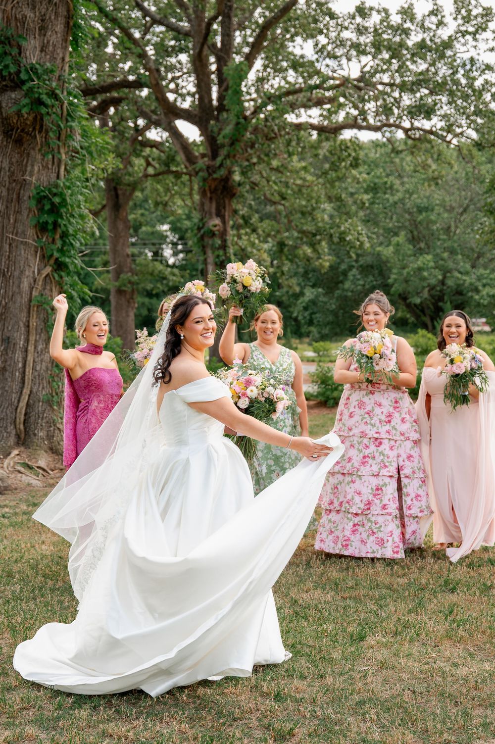 Bridal party celebrating on grass with flowing white wedding dress.