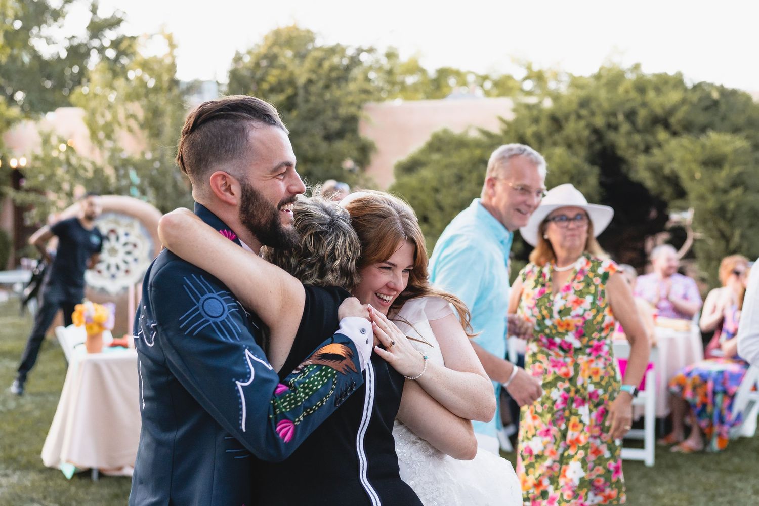 Newlyweds share a warm embrace with emotional wedding guests during joyful outdoor reception celebration. Casa De Suenos
