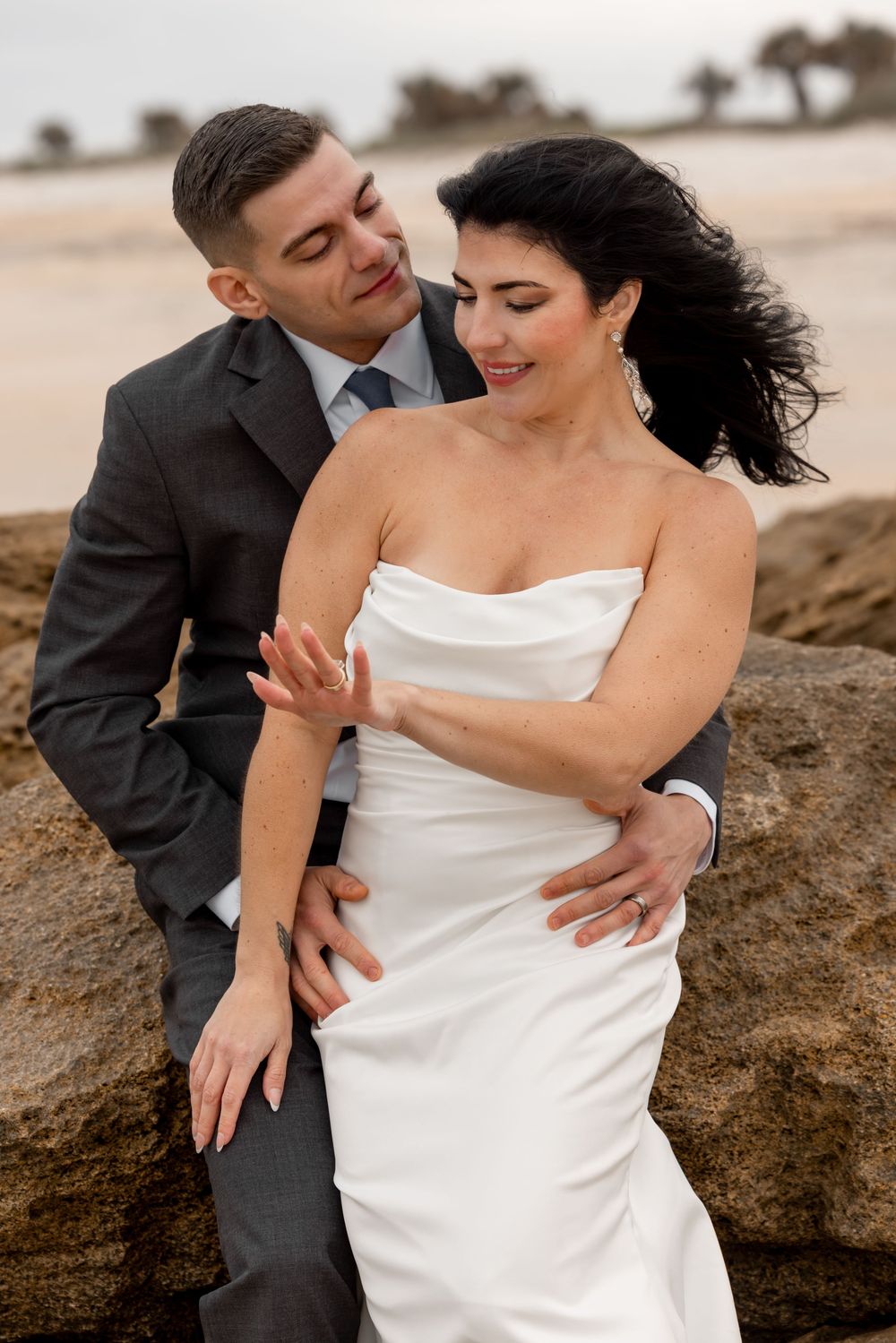 Intimate beach wedding portraits with couple sharing tender moments against coastal backdrop.