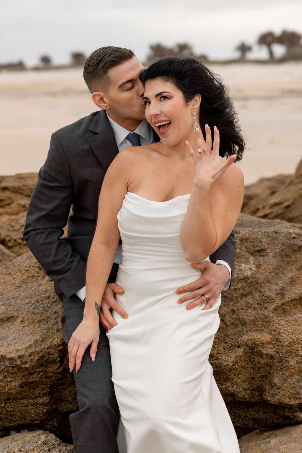 A romantic beach wedding photo series showing intimate moments between newlyweds against coastal rocks.