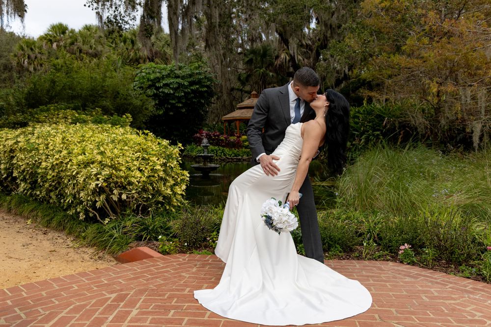 A couple in wedding attire share a romantic moment in a lush garden setting during their special day.