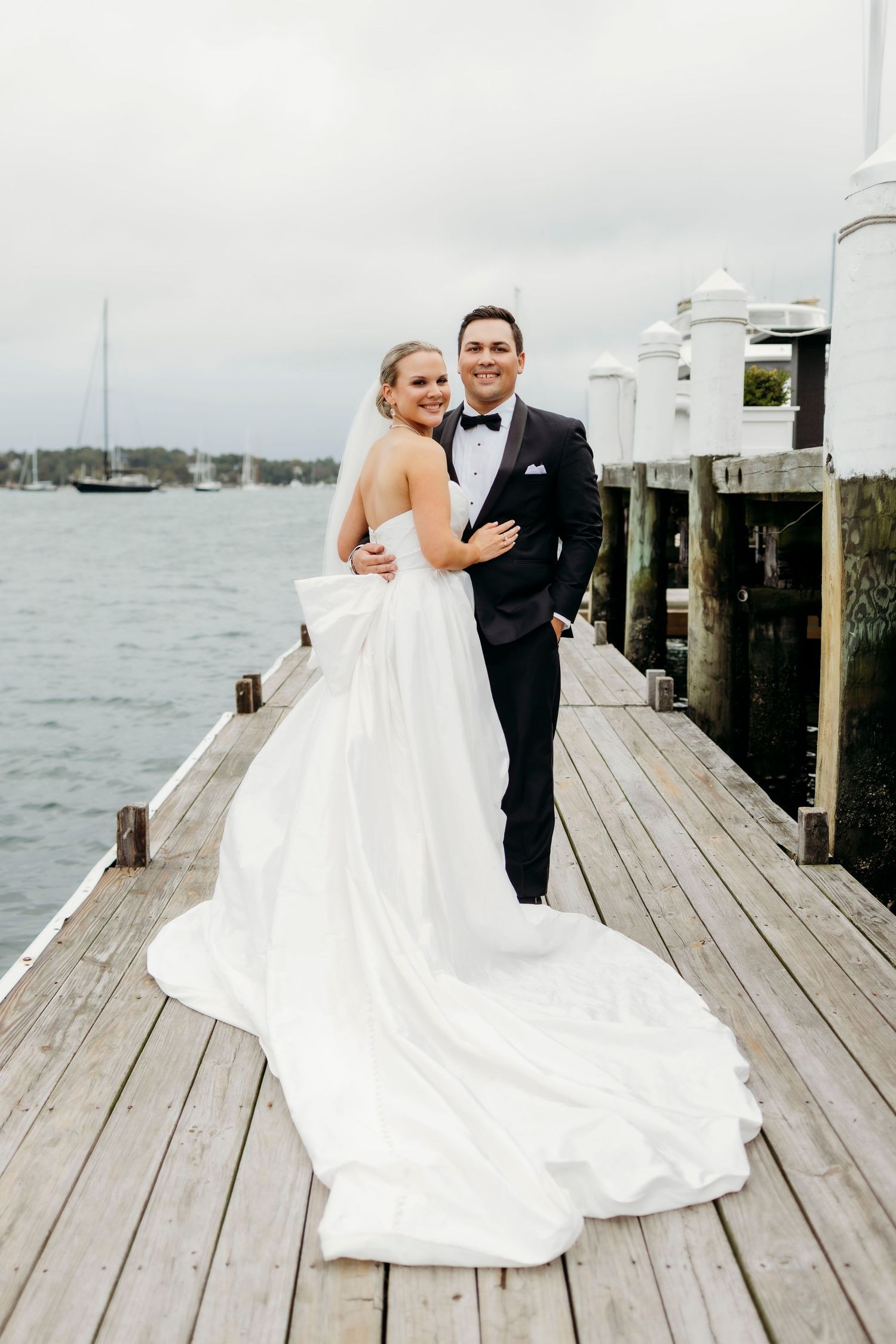 A bride and groom share a joyful embrace in a series of candid wedding photos with a vintage red car in the background.