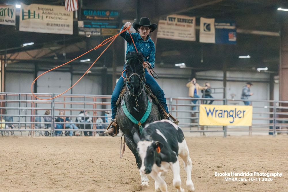 Wide view of indoor rodeo arena showing multiple riders competing during a western equestrian event.