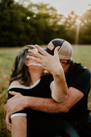 A close-up shot of an intimate embrace outdoors with a ring visible on one hand.
