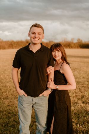 Couple poses together in a golden field during sunset for romantic portraits.