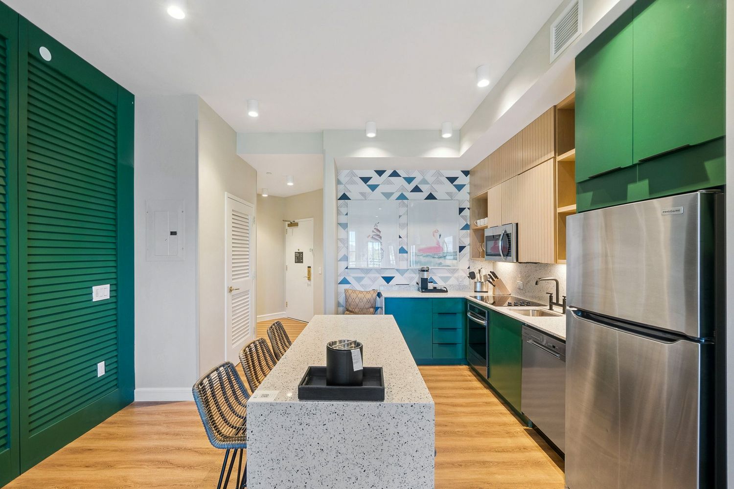 Modern office hallway with green accent walls, wood flooring, and recessed lighting creating a sleek professional environment.