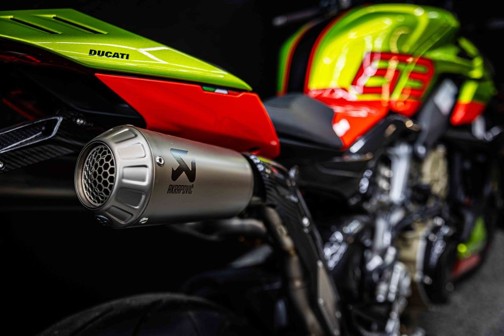 Close-up of a Ducati motorcycle exhaust with neon green and red bodywork visible.