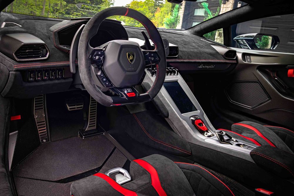 Modern Lamborghini interior featuring a sporty steering wheel and red accent details.
