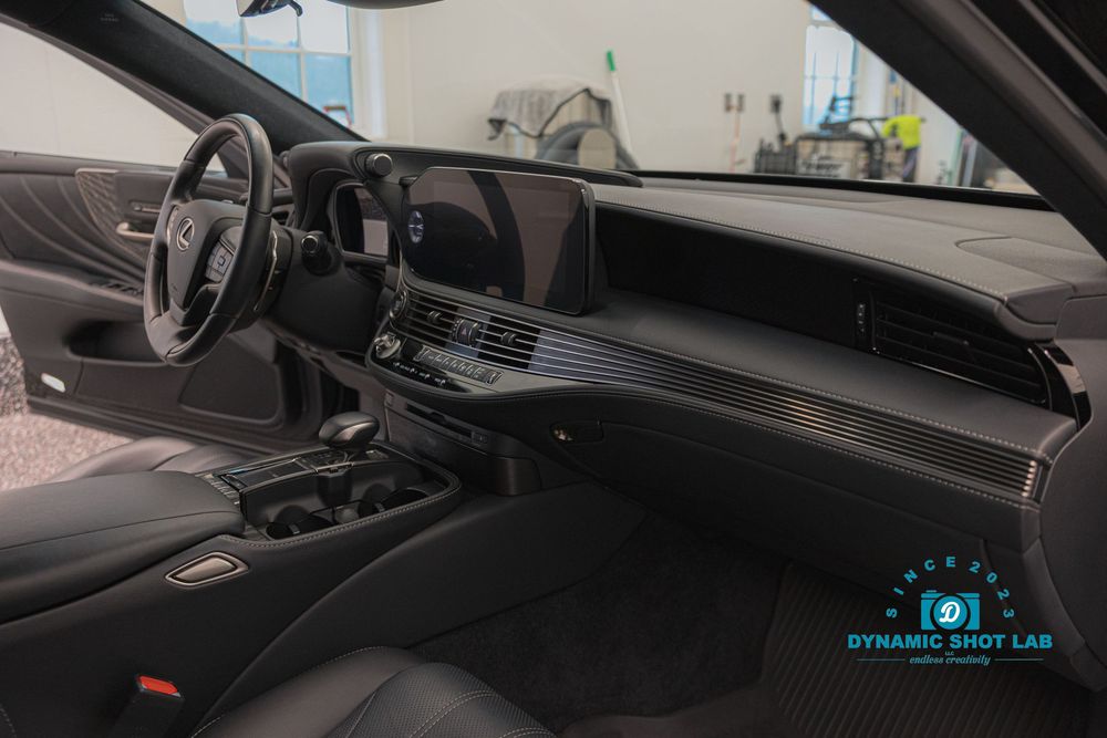 Luxurious Lexus interior showcasing a wide digital dashboard, carbon fiber trim, and premium black leather seats.