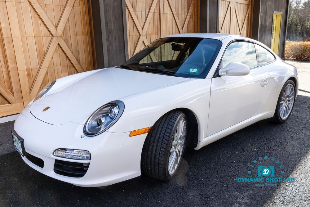 White Porsche 911 Carrera coupe parked outdoors, showcasing sleek design, silver wheels, and pristine condition.
