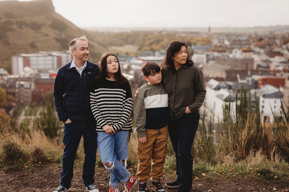 Group walking together on a hillside overlooking a residential neighborhood during golden hour.