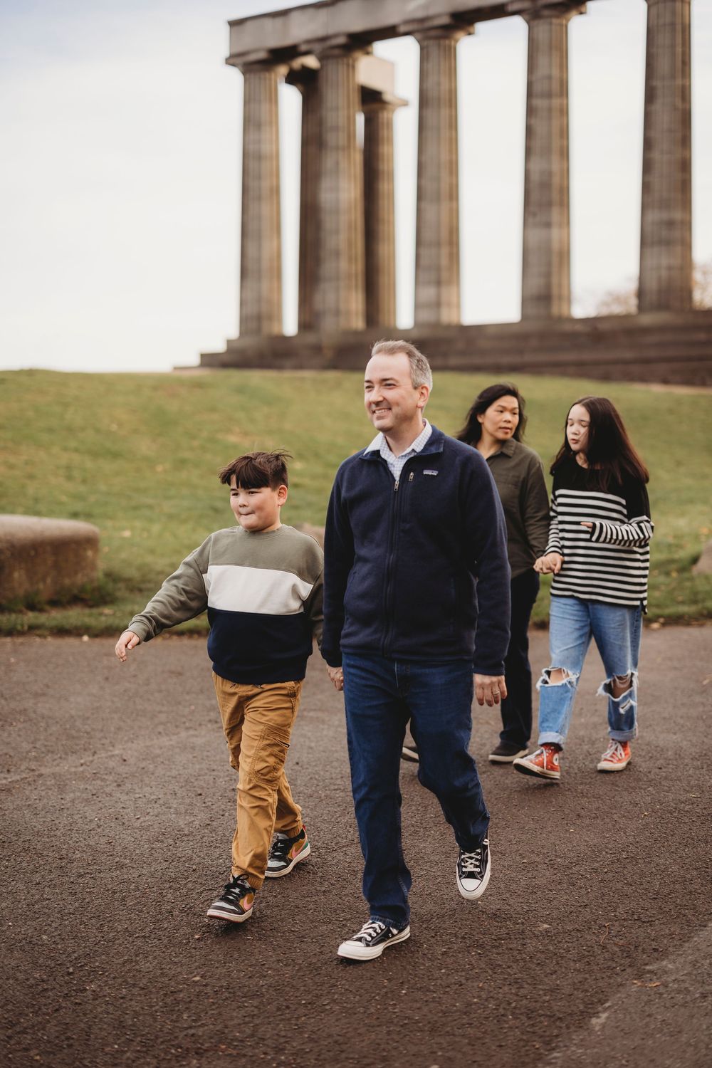 A family walks along a path near the National Monument of Scotland on Calton Hill in Edinburgh.