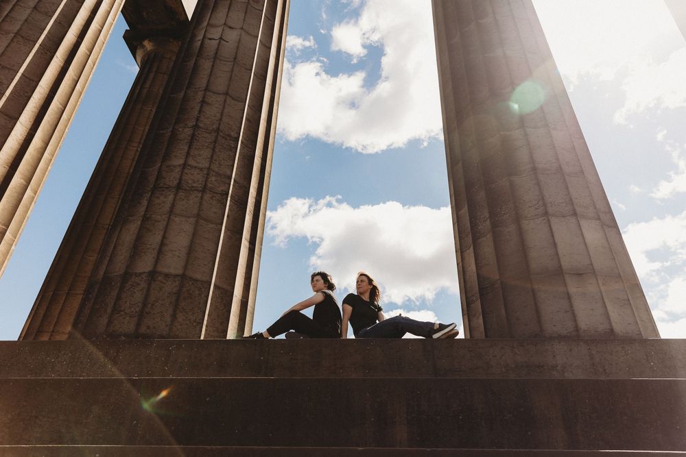 Dramatic upward view of towering stone columns against a blue sky with scattered white clouds.