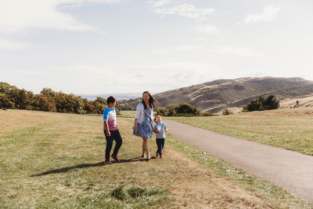 People hiking together on scenic mountain trails during a sunny afternoon in rolling grassland terrain.