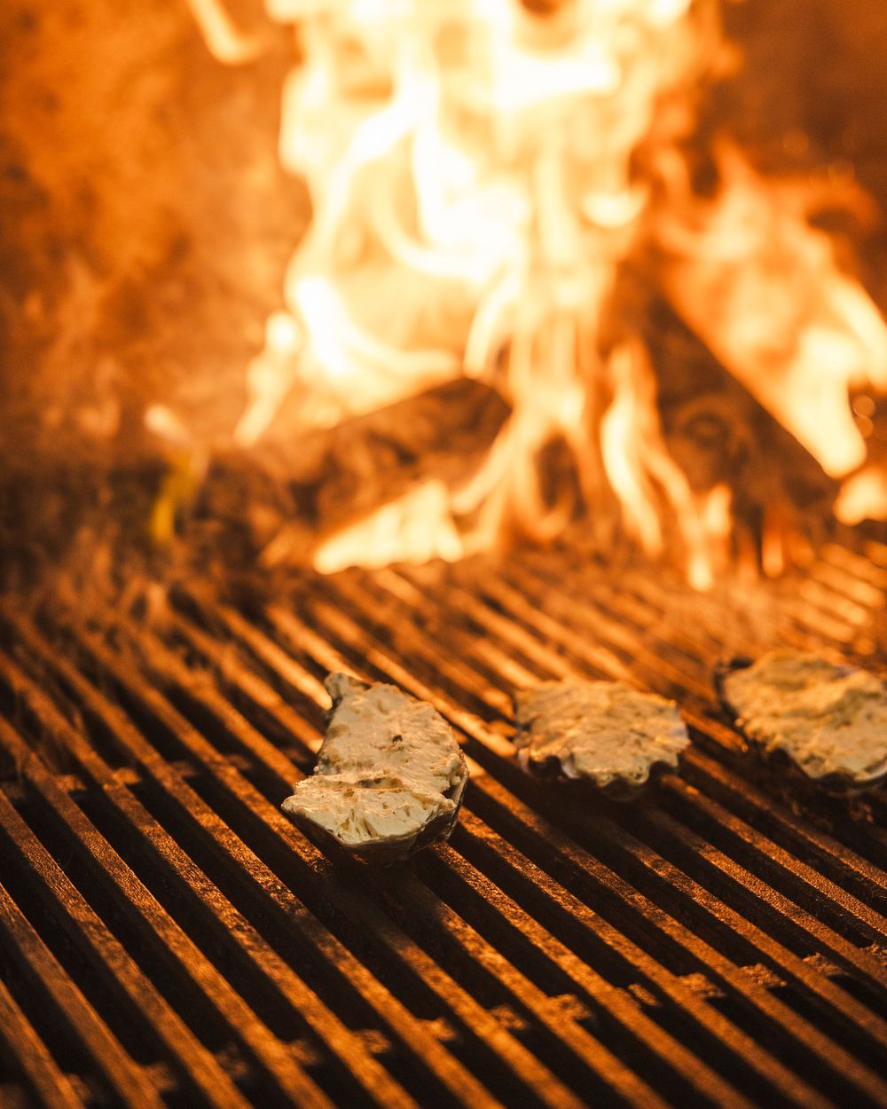 Flames dance over a hot grill grate, creating an intense cooking surface for barbecuing food.
