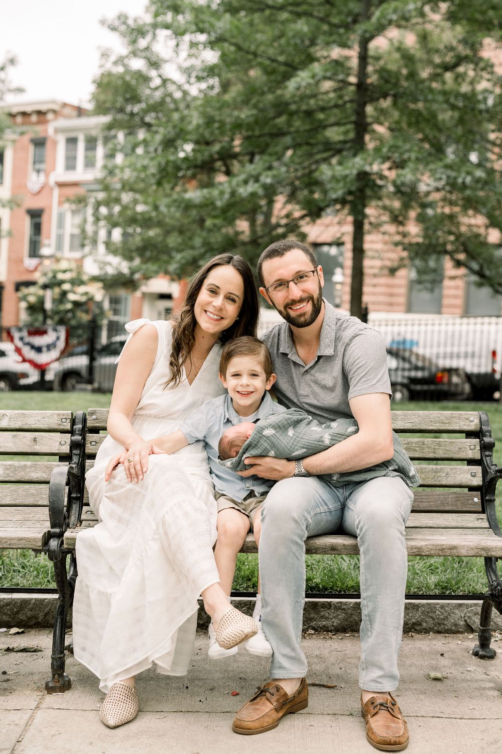 A family sits together on a park bench sharing sweet moments and smiles on a summer afternoon.