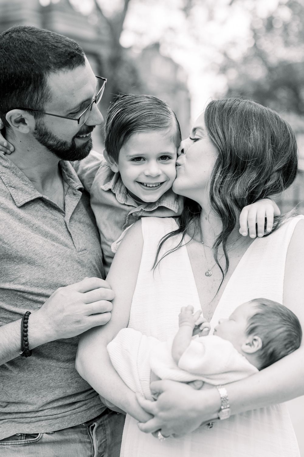 A heartwarming black and white photo series showing tender family moments on a sunny day outdoors.