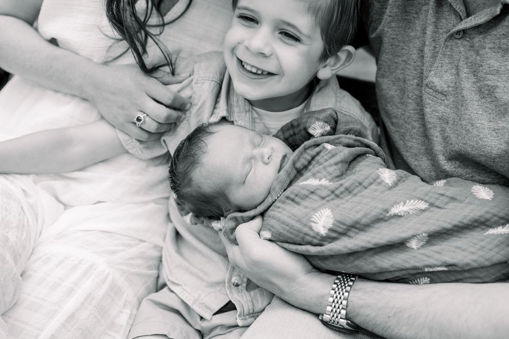Black and white photos show intimate moments of affection and connection between parent and child in bed.