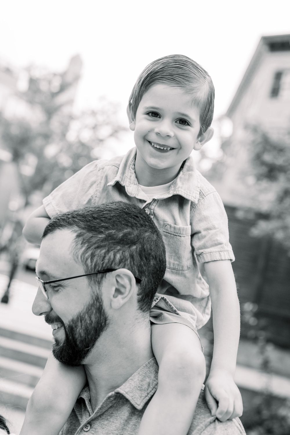 Black and white image showing a playful piggyback ride moment outdoors.