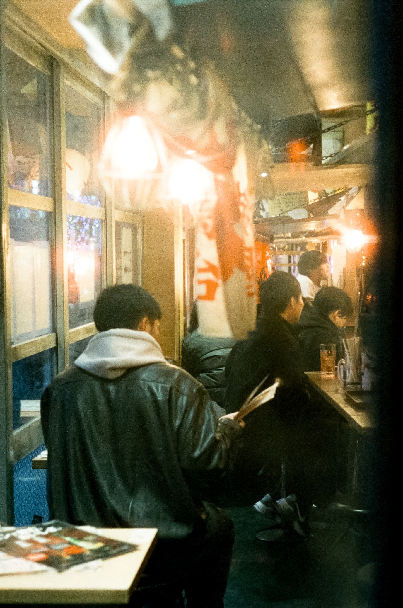 Dimly lit Japanese street at night with glowing lanterns and neon signs illuminating the narrow alleyway.