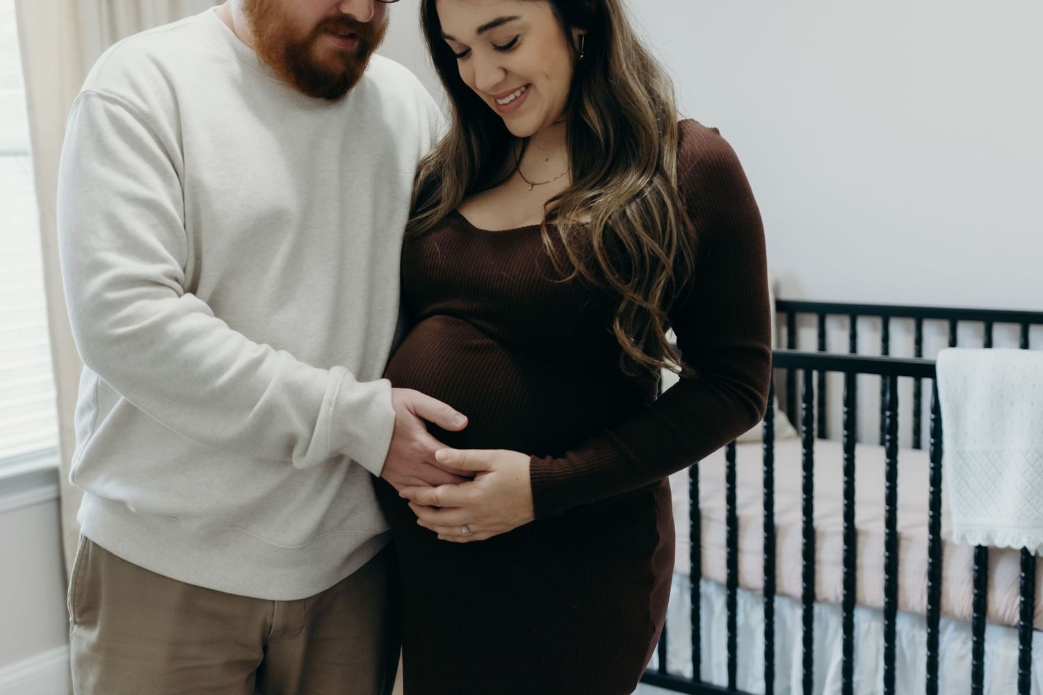 An expectant couple shares an intimate moment while cradling baby bump.