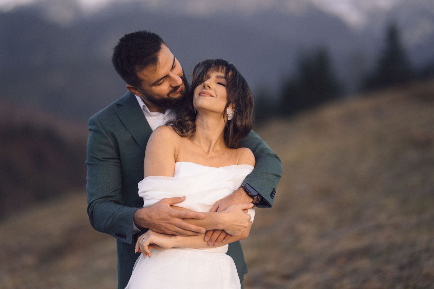 Romantic couple embraces on a scenic mountain trail during golden hour photography session.