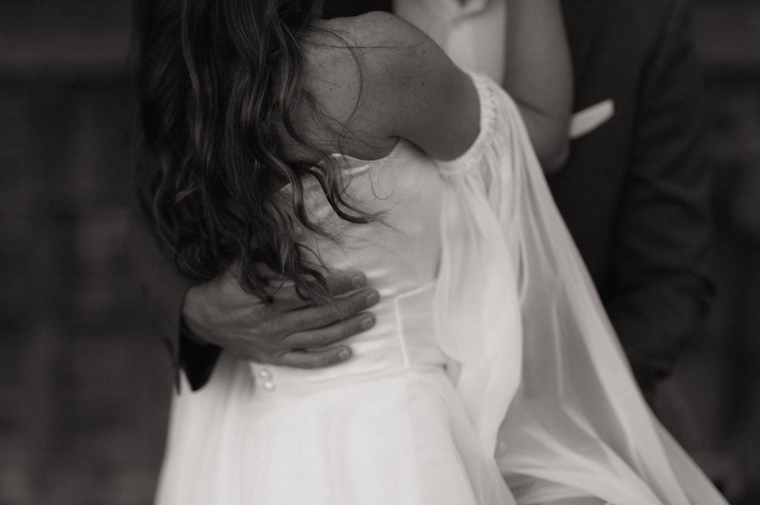 Black and white photo of a bride and groom dancing together at their wedding reception.