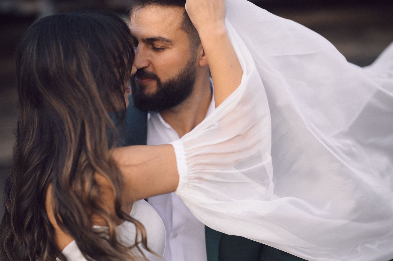 A romantic couple in white clothing share an intimate dance pose in a dark setting.