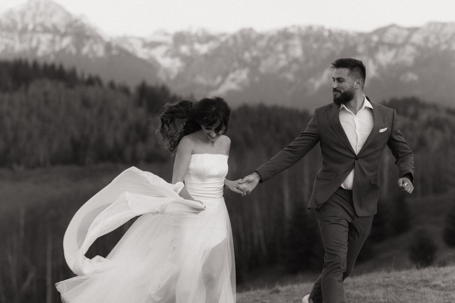 A black and white wedding photo series showing a couple dancing and embracing against a mountain landscape backdrop.