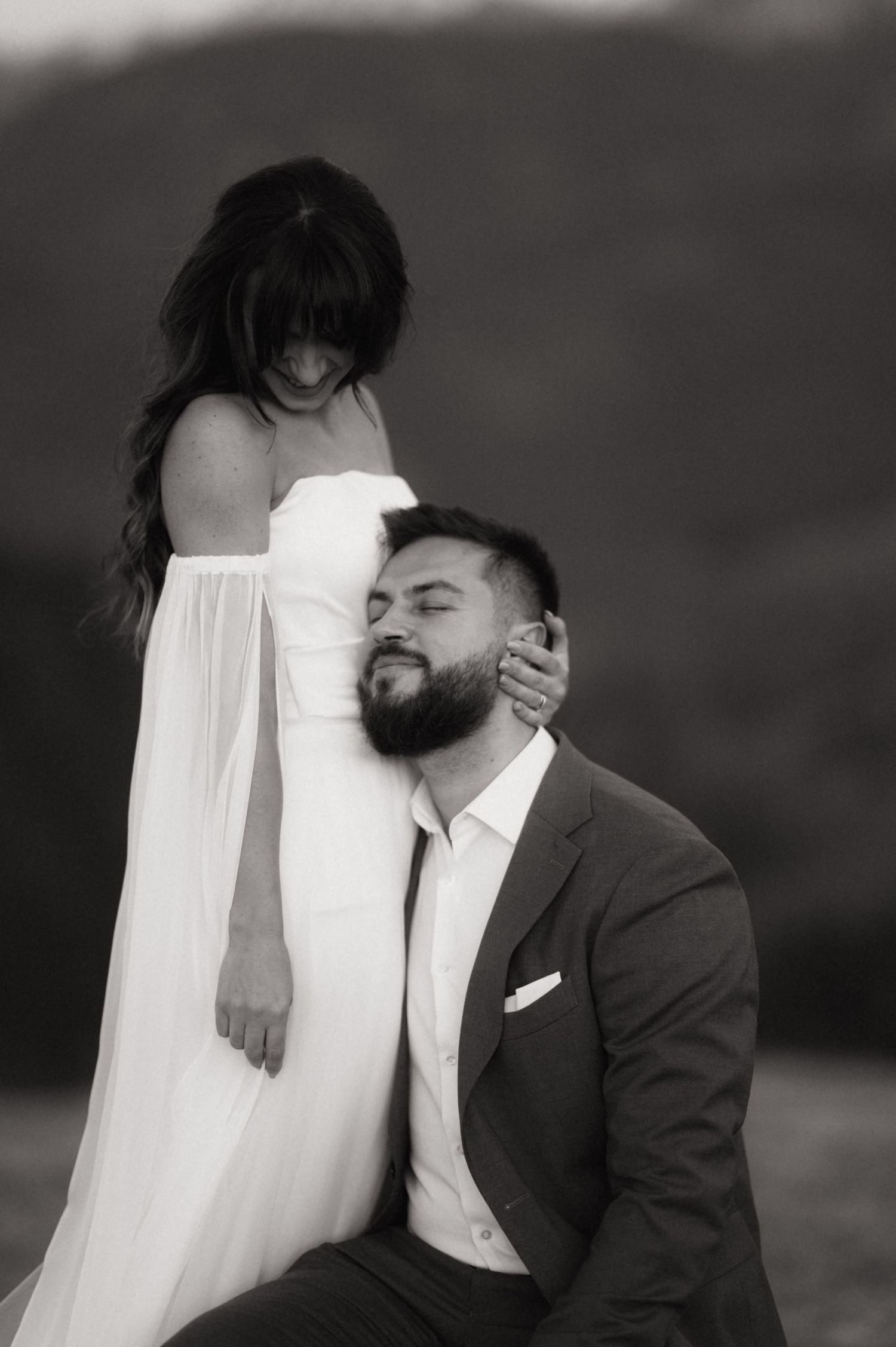Black and white wedding photo series showing intimate moments between a bride in white dress and groom in dark suit.