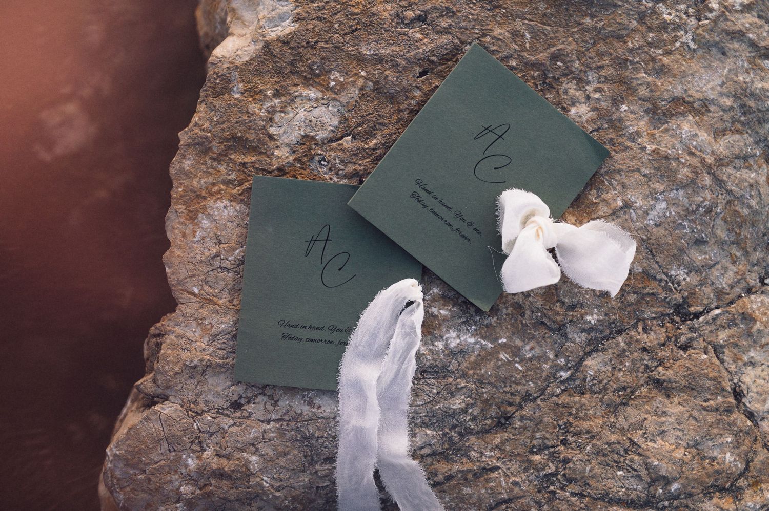 Two green passport-style documents with white ribbons lying on a textured stone surface.