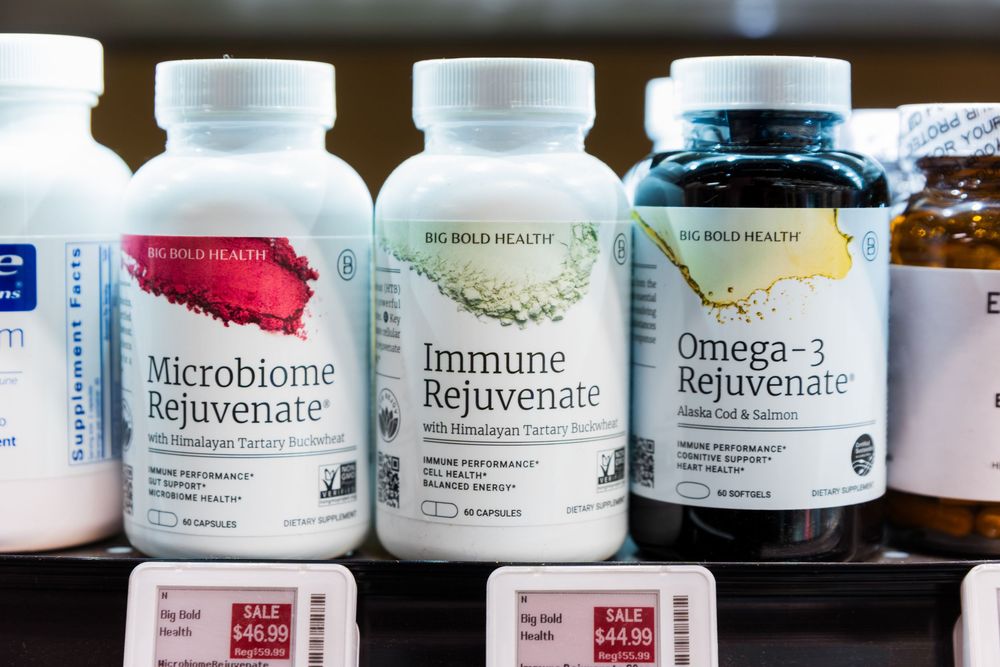 Various supplement bottles lined up on wooden shelves showing vitamins and wellness products.