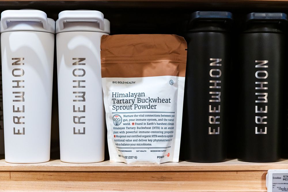 White and black supplement bottles arranged neatly on wooden shelving display.