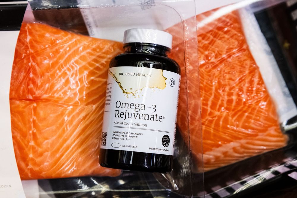 Fresh raw salmon fillets displayed next to supplement bottles.