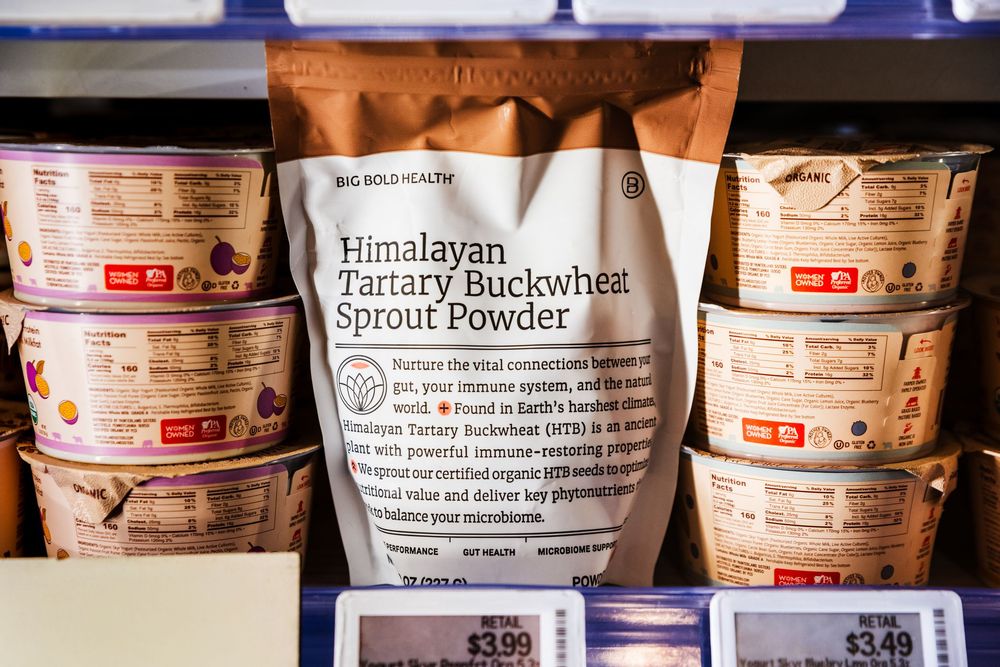 Multiple jars of Himalayan buckwheat and other health food powders lined up on a shelf in a store display.