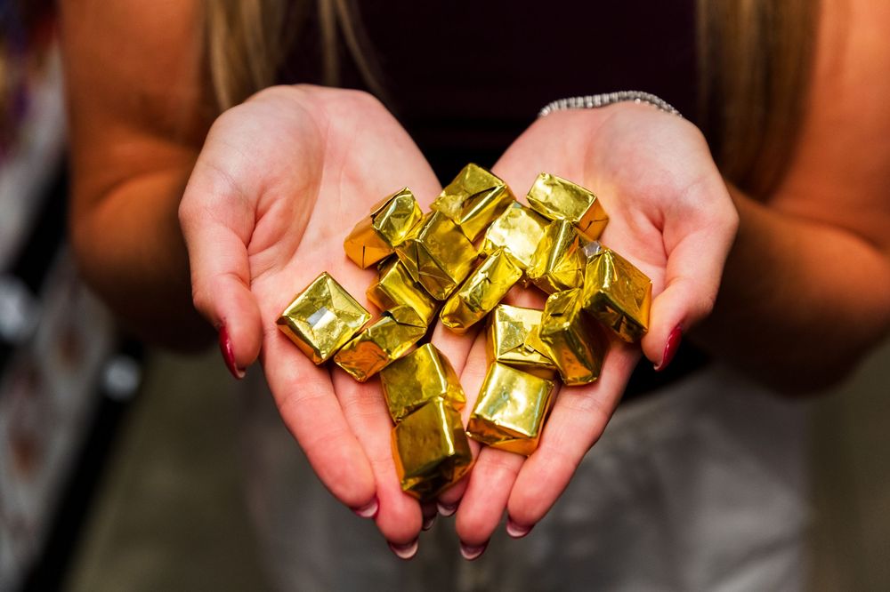 Hands holding and displaying multiple golden supplement capsules.