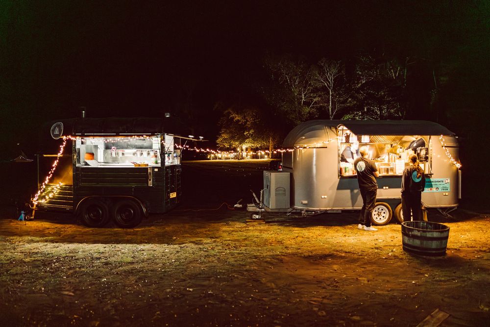 Nighttime outdoor event with illuminated tents and vendor stalls creating a warm, festive atmosphere.