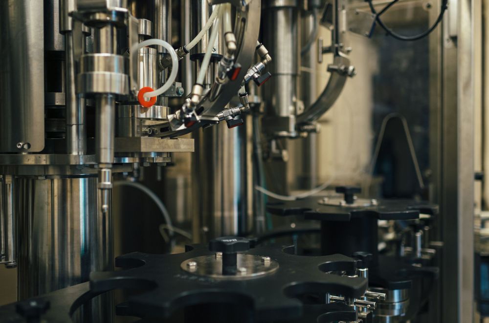 Detail of industrial filling machinery with multiple nozzles and mechanical components.