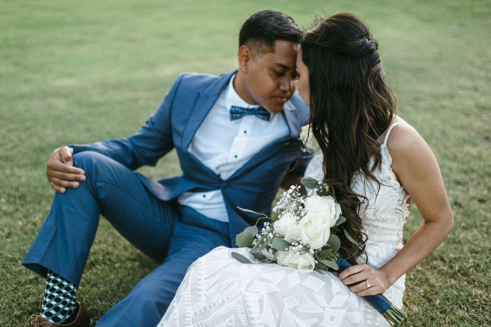 A couple shares a romantic moment while resting on a grassy hillside.