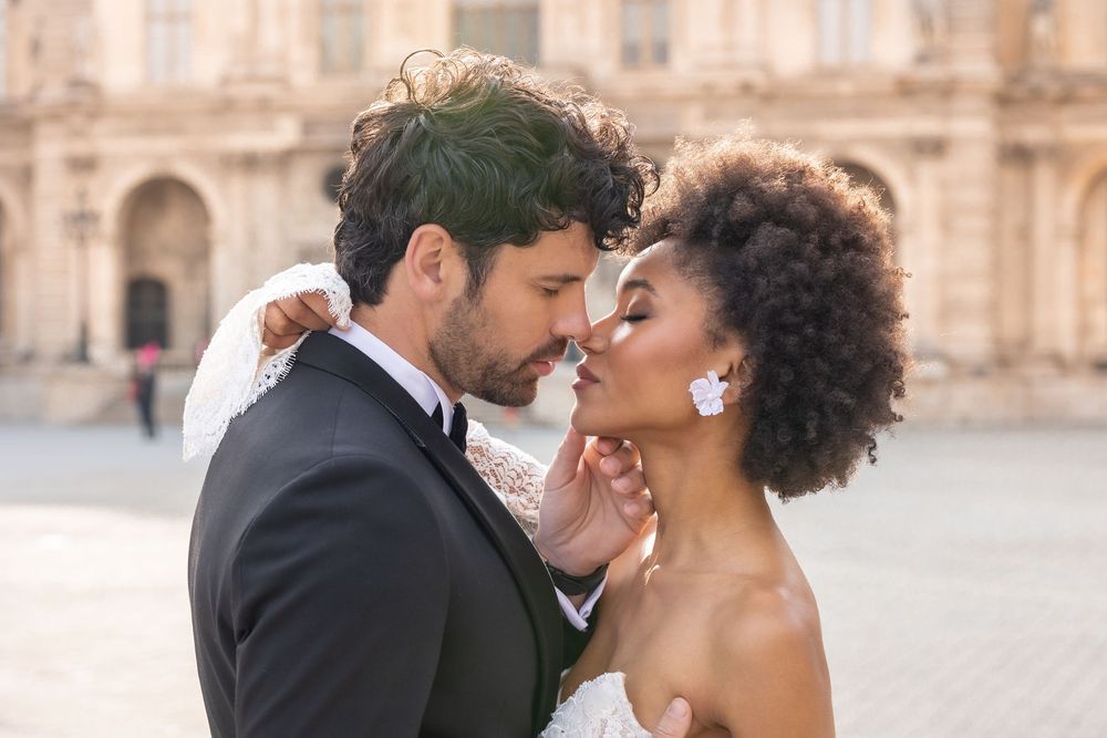 Romantic couple in formal attire share intimate moments in front of historic European architecture.